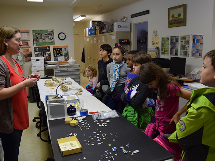 Employee showing artifacts to a group of students